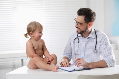 Photo of Pediatrician examining cute little baby in clinic