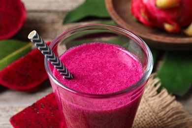 Photo of Glass of tasty pitahaya smoothie with straw on table, closeup view