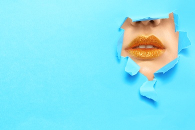 Photo of View of beautiful young woman with creative lips makeup through hole in color paper