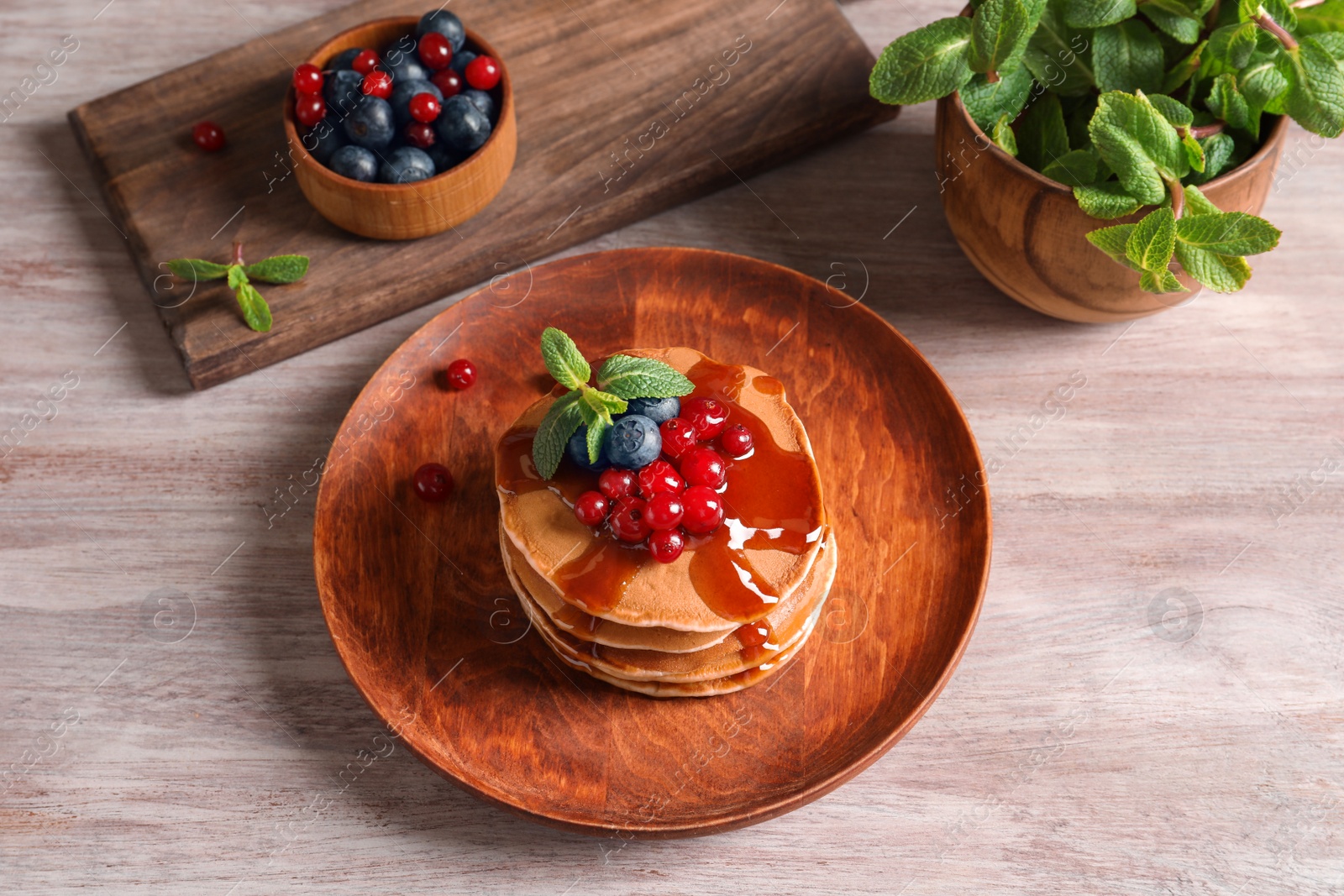 Photo of Stack of tasty pancakes with berries and syrup on table