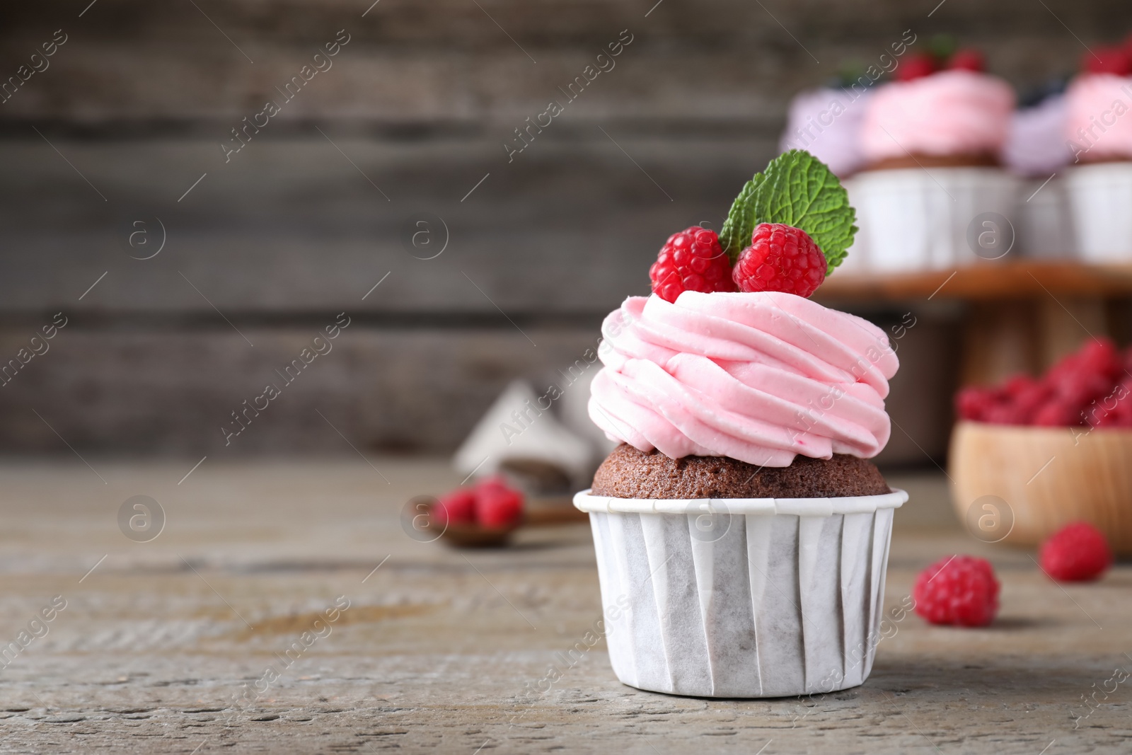 Photo of Sweet cupcake with fresh raspberries on wooden table. Space for text