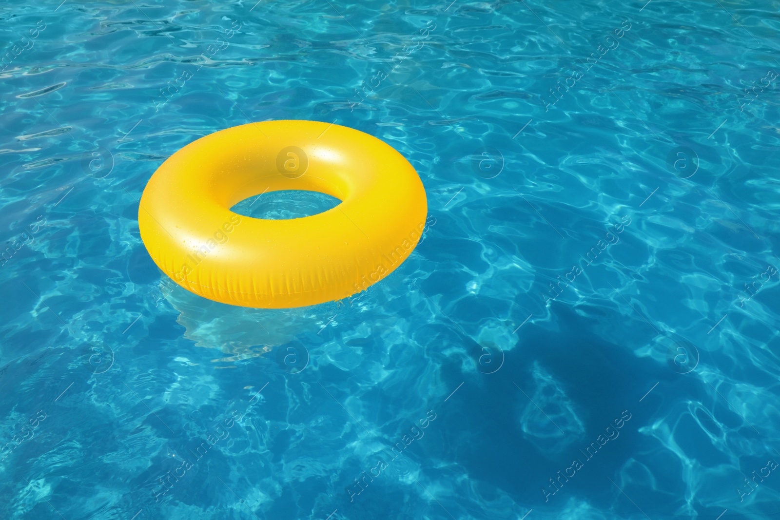 Photo of Inflatable ring floating in swimming pool on sunny day. Space for text