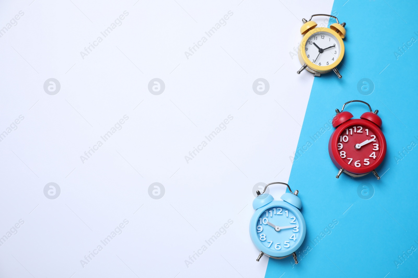 Photo of Modern alarm clocks on color background, flat lay. Space for text