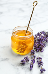 Photo of Tasty honey and lavender flowers on white marble table
