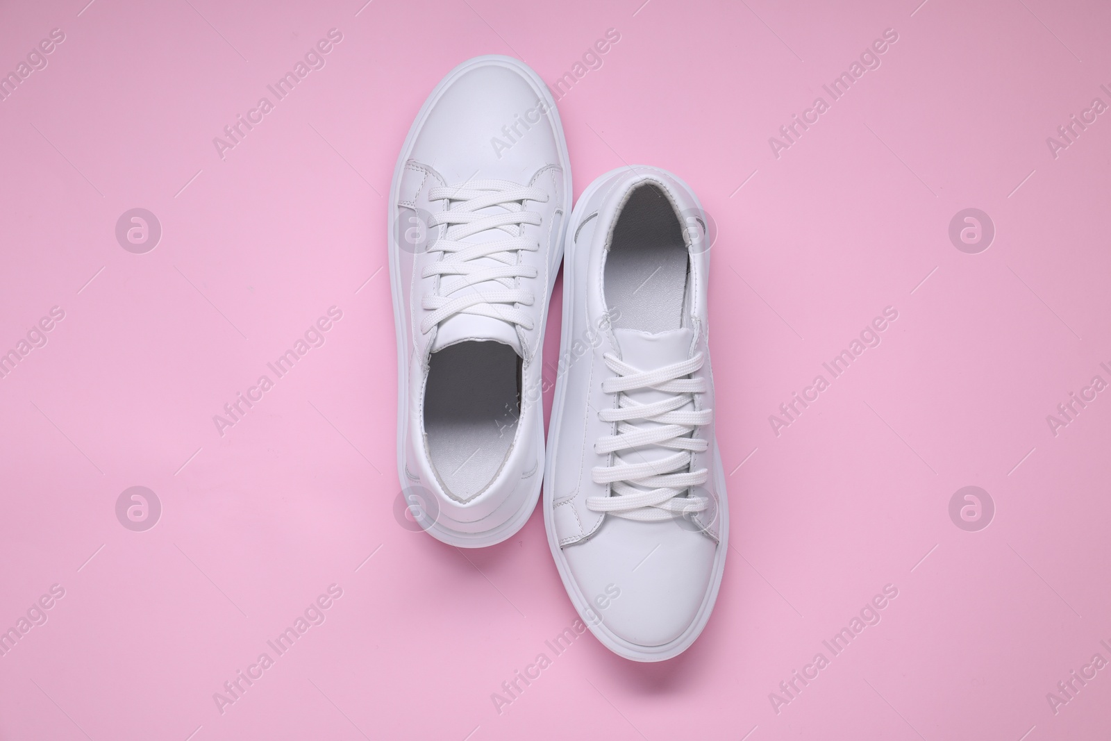 Photo of Pair of stylish white sneakers on pink background, top view