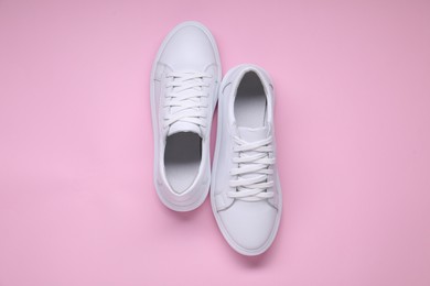 Photo of Pair of stylish white sneakers on pink background, top view