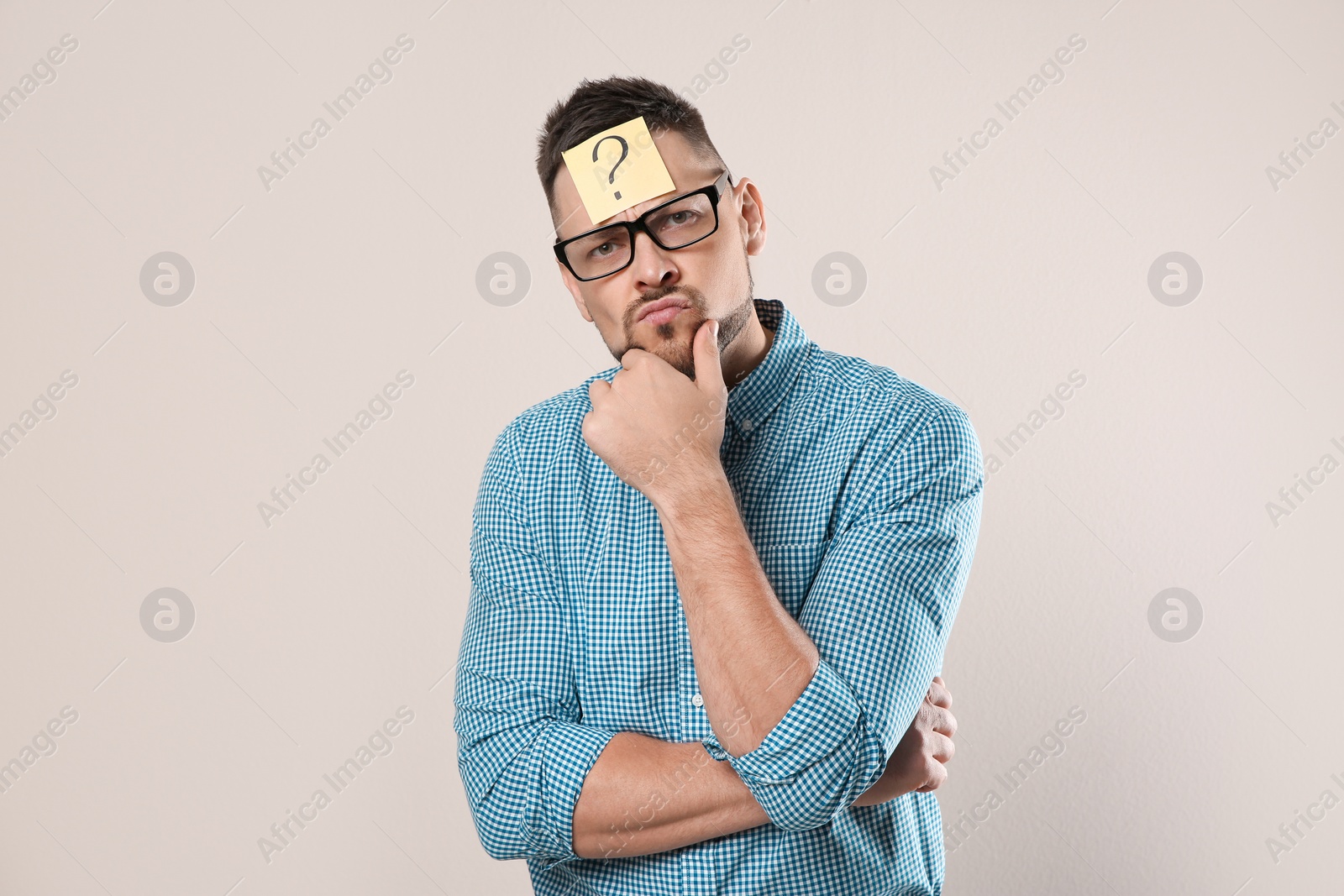 Photo of Emotional man in eyeglasses with question mark on grey background