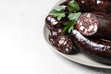 Tasty blood sausages with parsley served on light grey table, closeup. Space for text