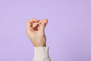 Photo of Man snapping fingers on violet background, closeup of hand. Space for text