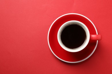 Aromatic coffee in cup on red background, top view. Space for text