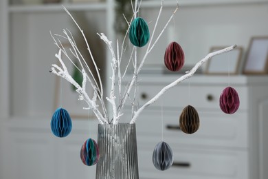 Branches with paper eggs in vase indoors. Beautiful Easter decor