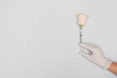 Doctor making injection to rose on light grey background, top view. Space for text