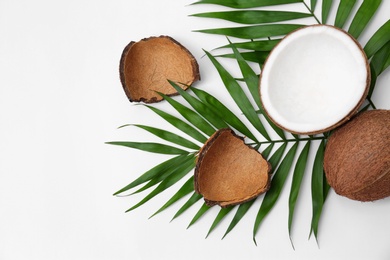 Fresh coconuts and palm leaves on white background, top view