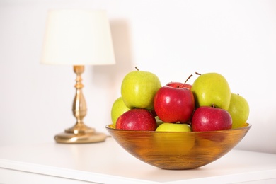 Bowl with different sweet apples on commode in room, space for text