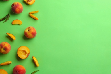 Flat lay composition with fresh peaches on green background. Space for text