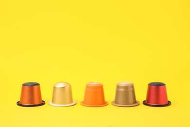 Photo of Many plastic coffee capsules on yellow background