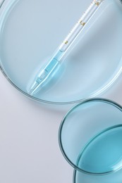 Photo of Measuring pipette and petri dishes on white table, flat lay