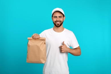 Photo of Young courier with paper bag on color background. Food delivery service