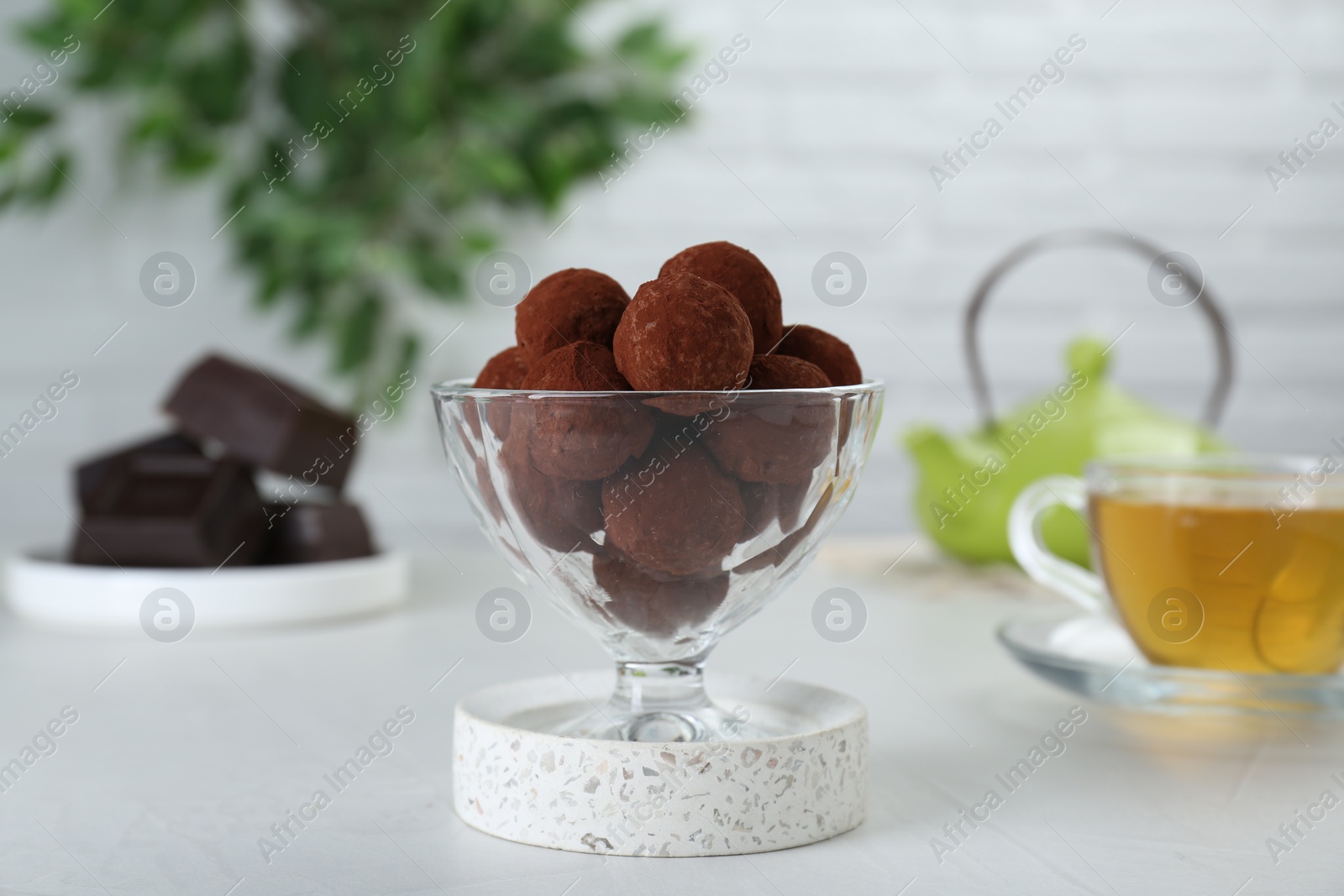 Photo of Dessert glass of delicious chocolate candies powdered with cocoa on white table