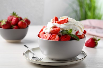 Photo of Delicious strawberries with whipped cream served on white wooden table