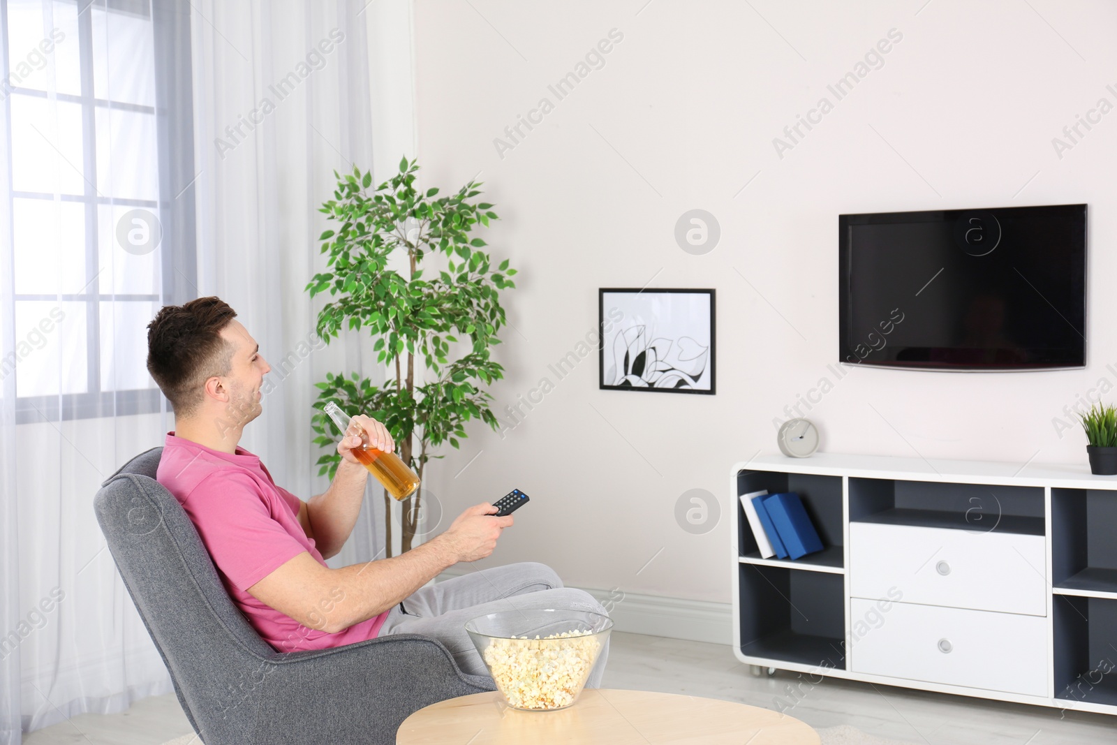 Photo of Handsome young man watching TV in armchair at home