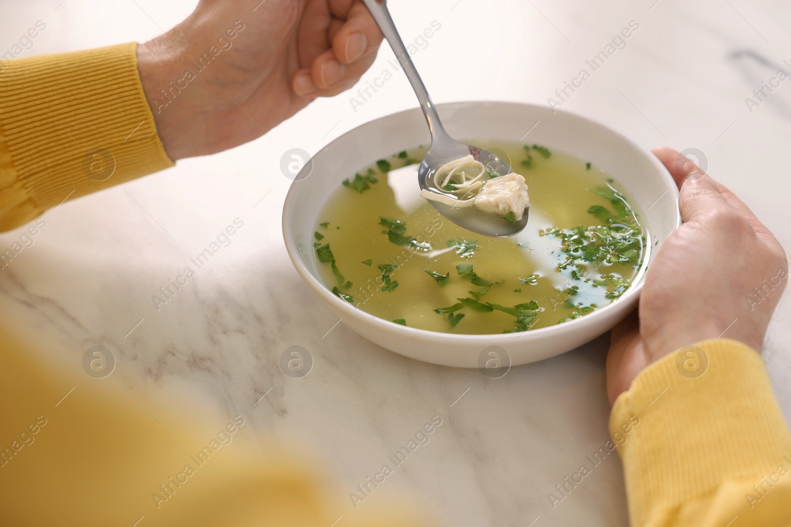 Photo of Man eating delicious chicken soup at light marble table, closeup