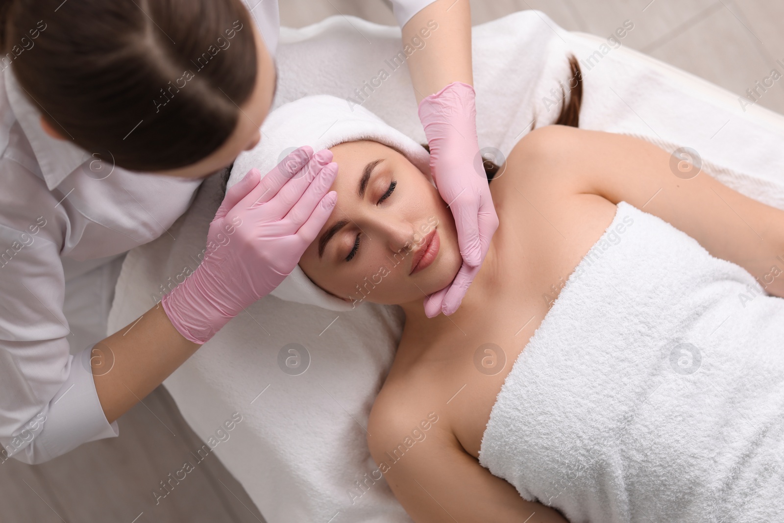 Photo of Cosmetologist making face massage to client, top view