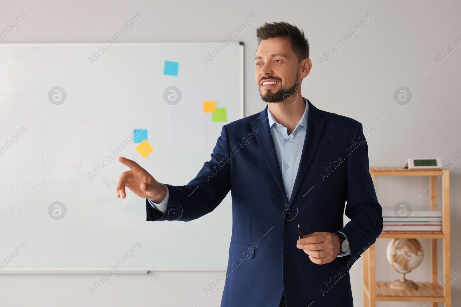 Photo of Happy teacher explaining mathematics at whiteboard in classroom