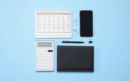 Photo of Smartphone and stationery on light blue background, flat lay