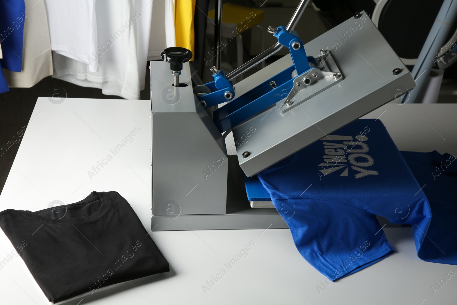 Photo of Printing logo. Heat press with blue t-shirt on white table