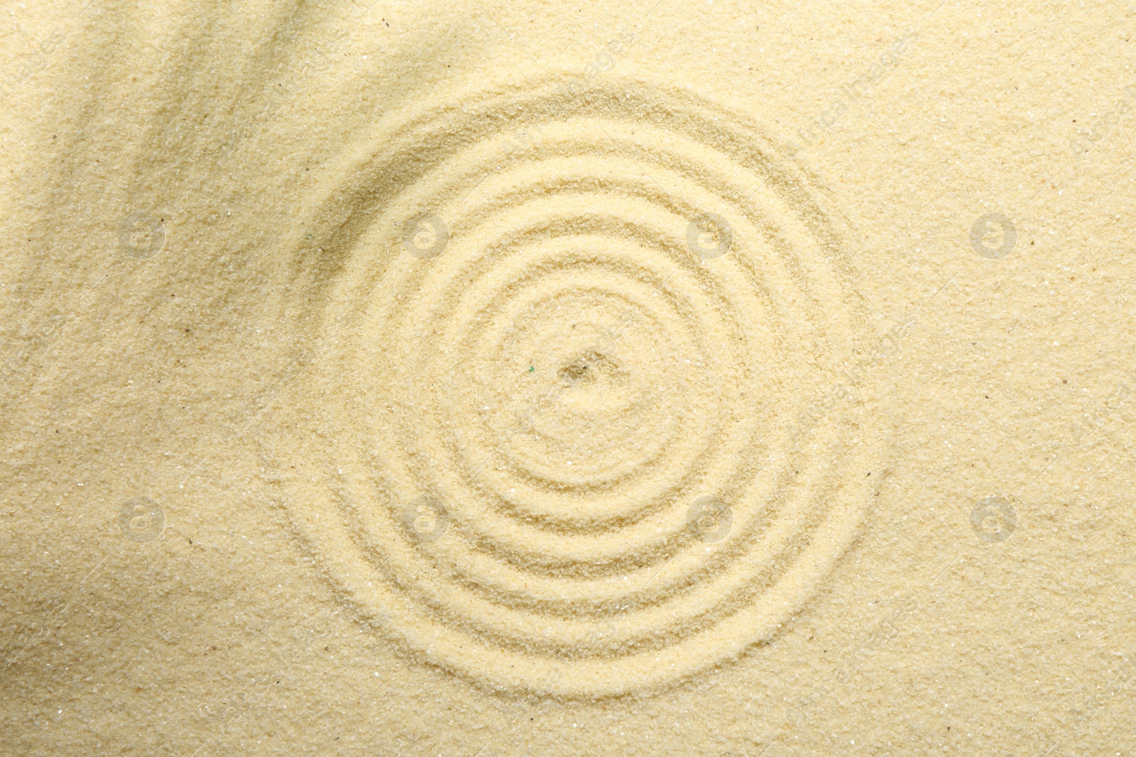 Photo of Zen rock garden. Circle pattern on beige sand, top view