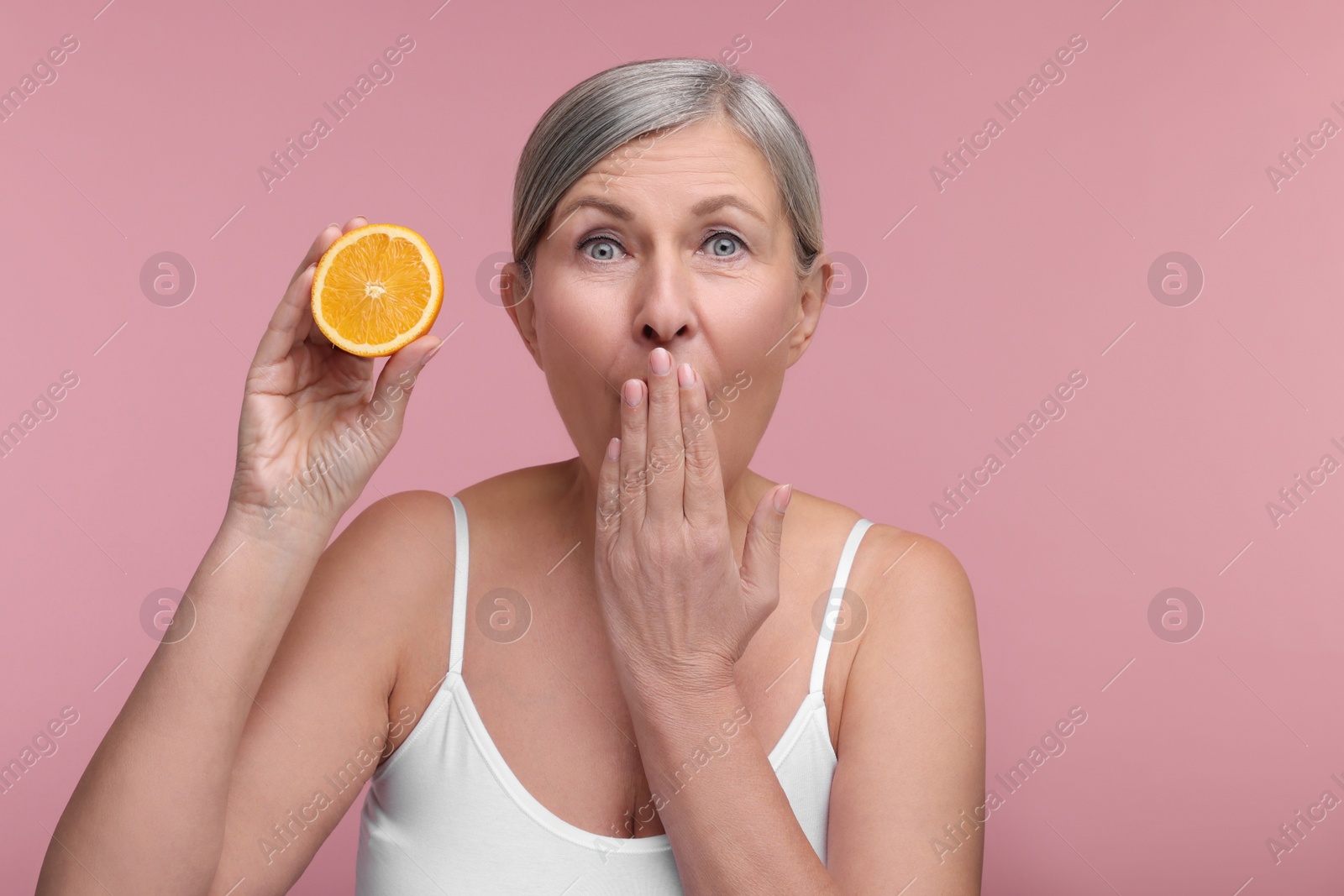 Photo of Beautiful woman with half of orange rich in vitamin C on pink background