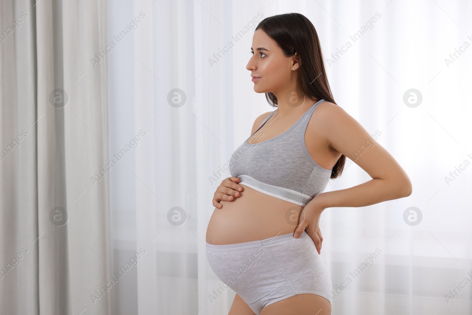 Photo of Beautiful pregnant woman in comfortable maternity underwear indoors, space for text