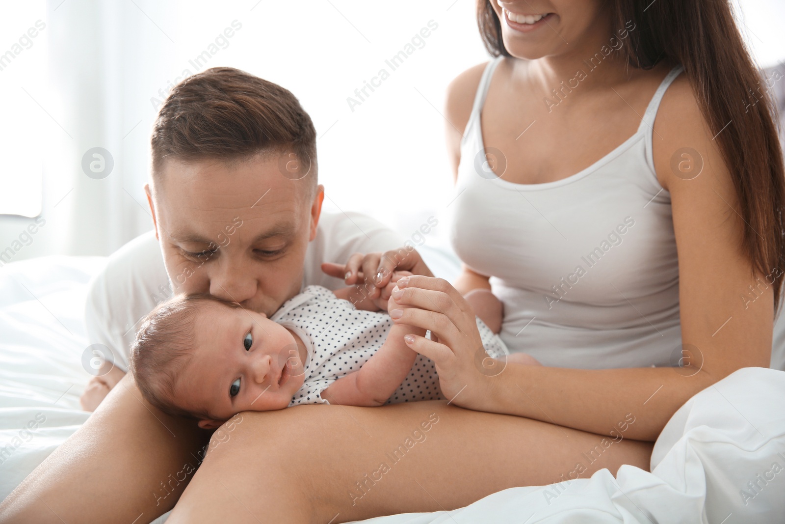 Photo of Happy couple with their newborn baby on bed