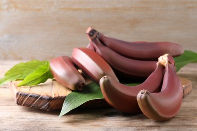 Photo of Delicious red baby bananas on wooden table