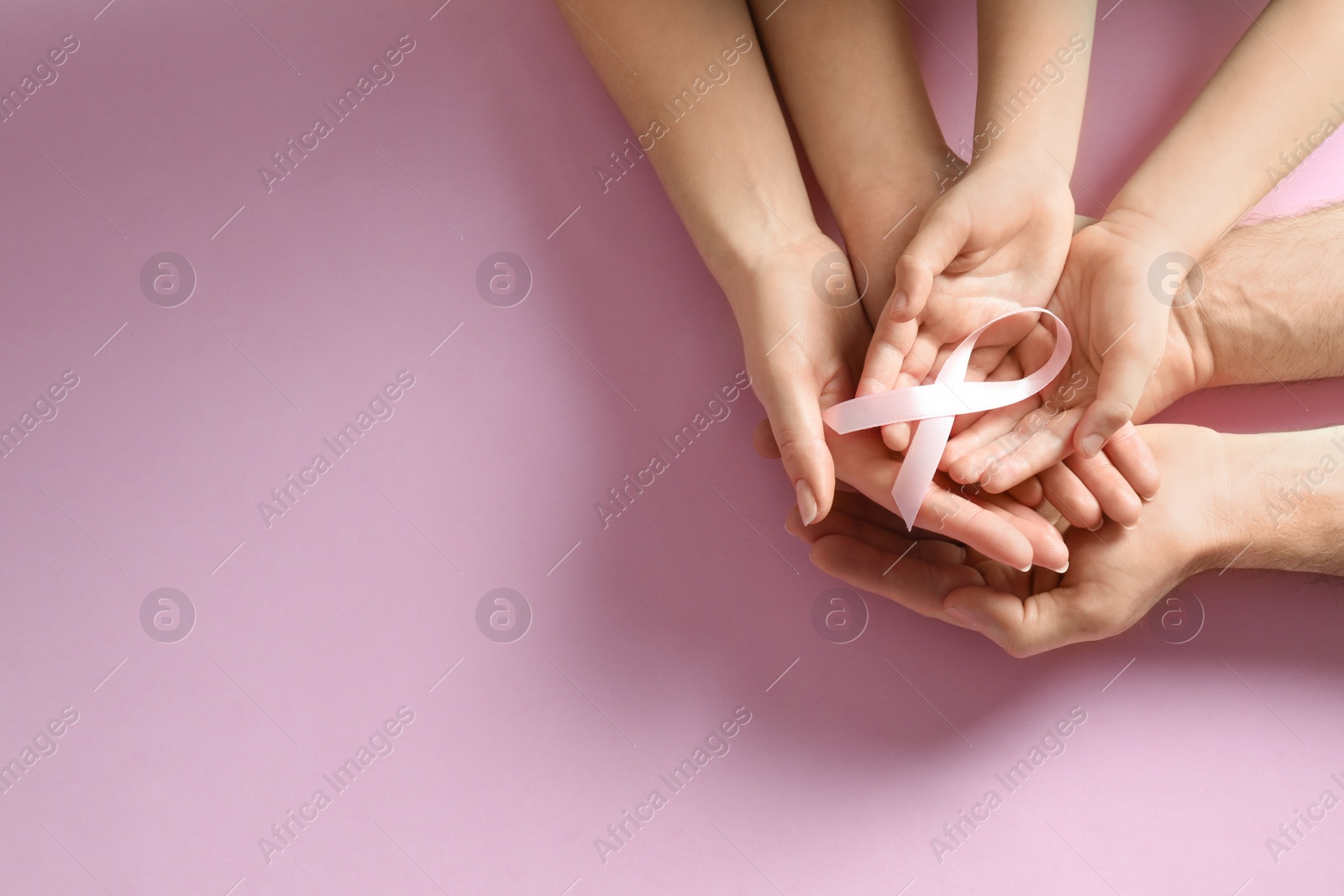 Photo of Family holding pink ribbon on color background, top view with space for text. Breast cancer awareness