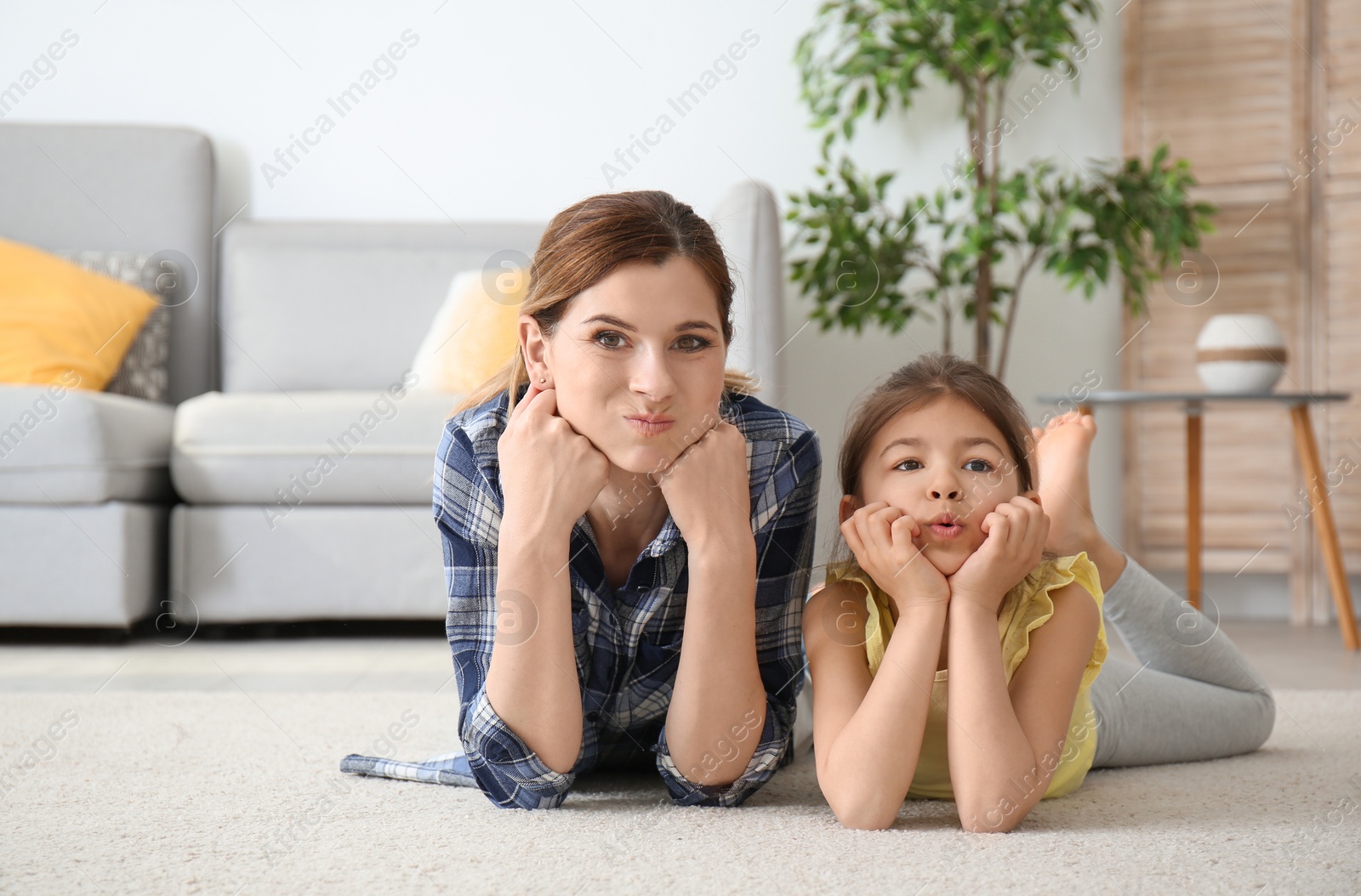 Photo of Cute little girl and her mother lying on cozy carpet at home