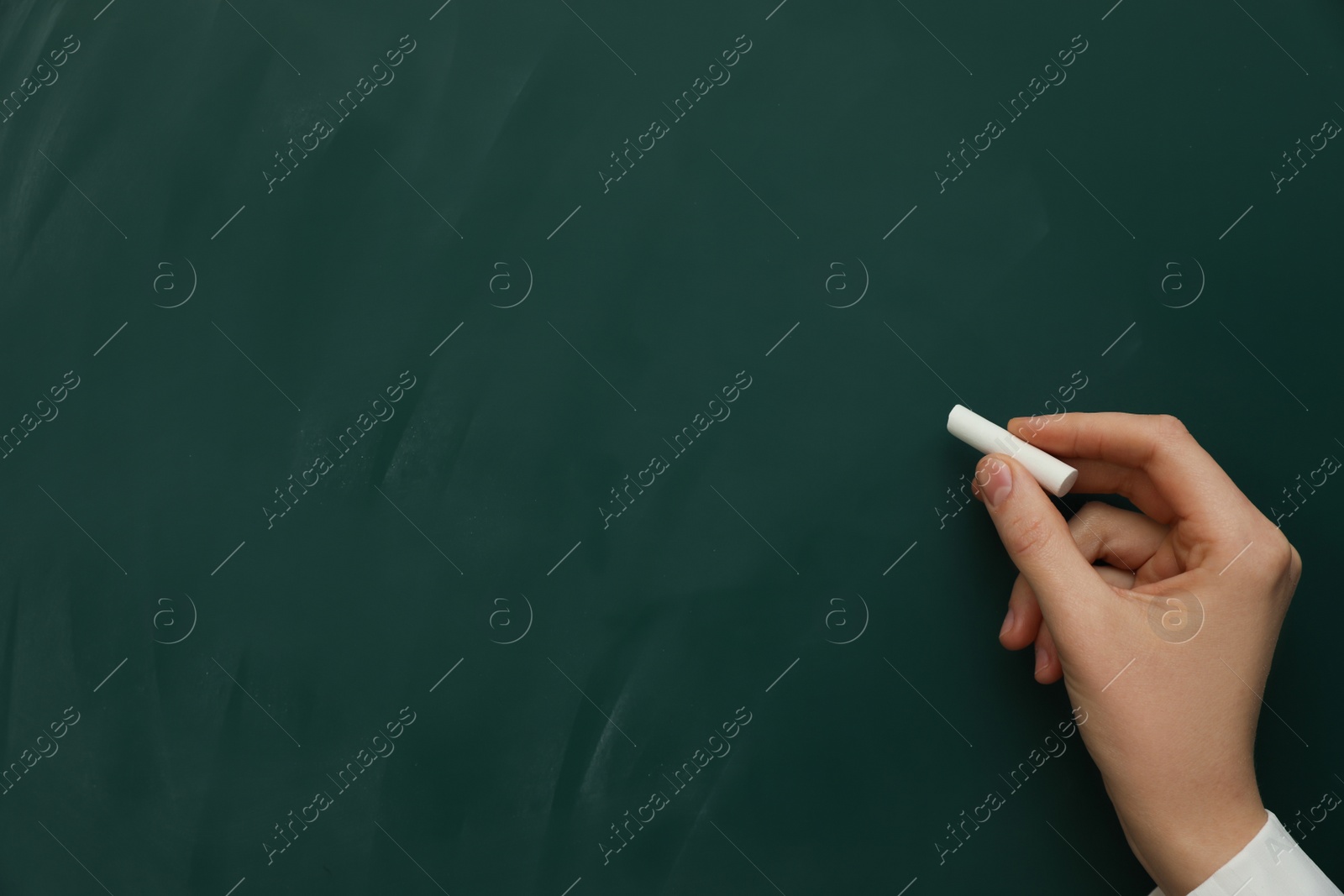 Photo of Woman with white chalk near green board, closeup. Space for text