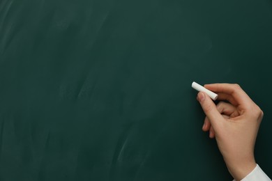 Photo of Woman with white chalk near green board, closeup. Space for text