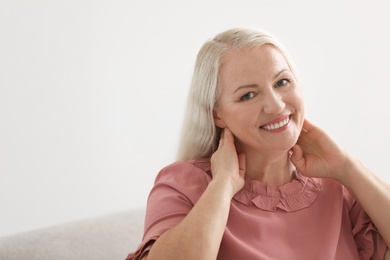 Portrait of beautiful older woman against light background with space for text