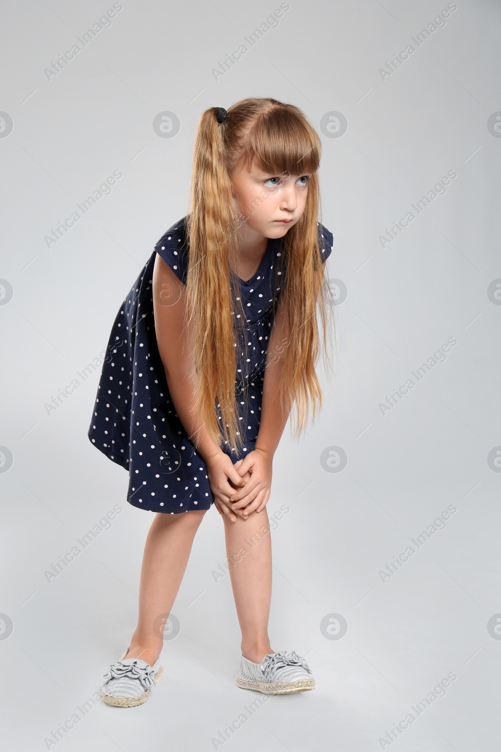 Photo of Full length portrait of little girl having knee problems on grey background