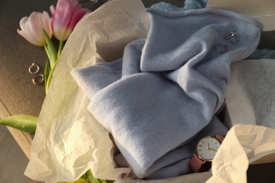 Photo of Soft cashmere sweater, accessories and tulips on sofa