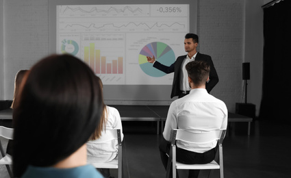 Photo of Male business trainer giving lecture in conference room with projection screen