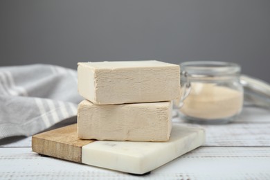 Photo of Blocks of compressed yeast on white wooden table, closeup