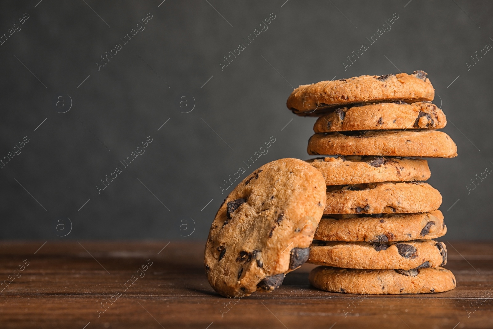 Photo of Stack of tasty chocolate chip cookies on wooden table. Space for text
