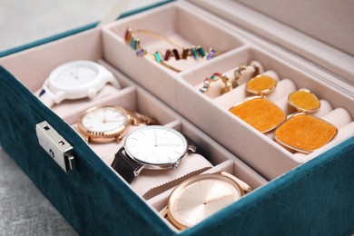 Photo of Elegant jewelry box with beautiful bijouterie and expensive wristwatches on table, closeup