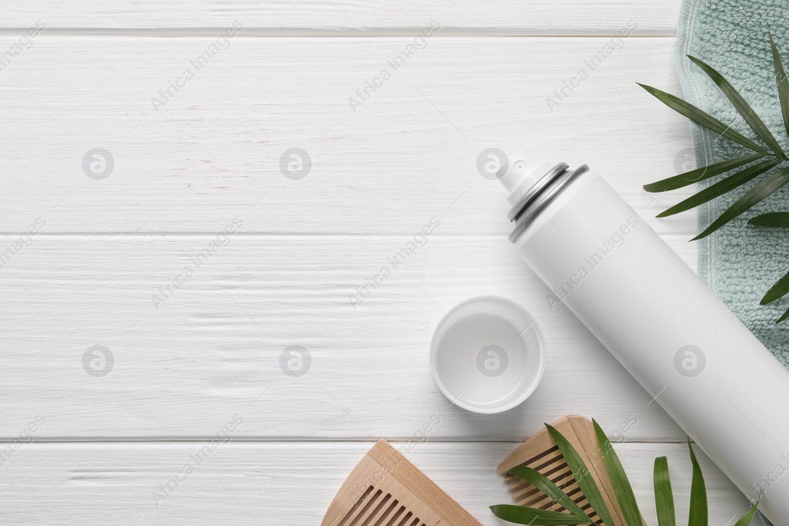 Photo of Dry shampoo spray, combs, towel and green twigs on white wooden table, flat lay. Space for text