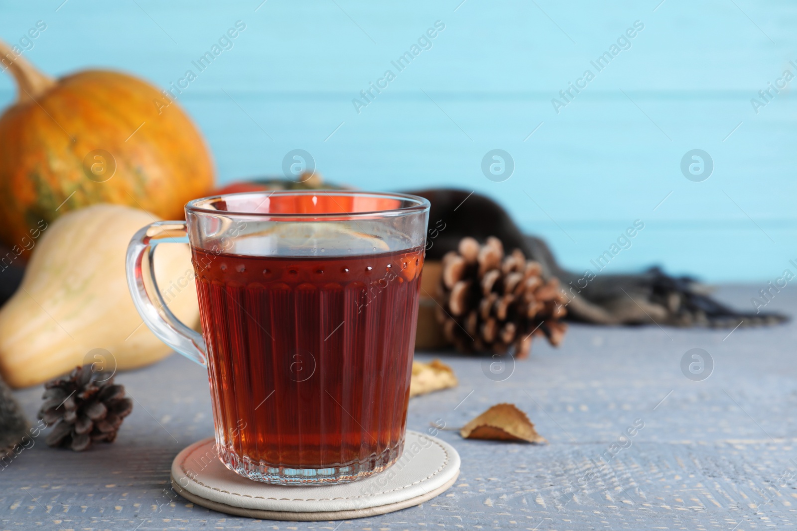 Photo of Cup of hot drink on grey wooden table against blue background. Cozy autumn atmosphere