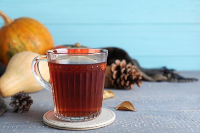 Photo of Cup of hot drink on grey wooden table against blue background. Cozy autumn atmosphere