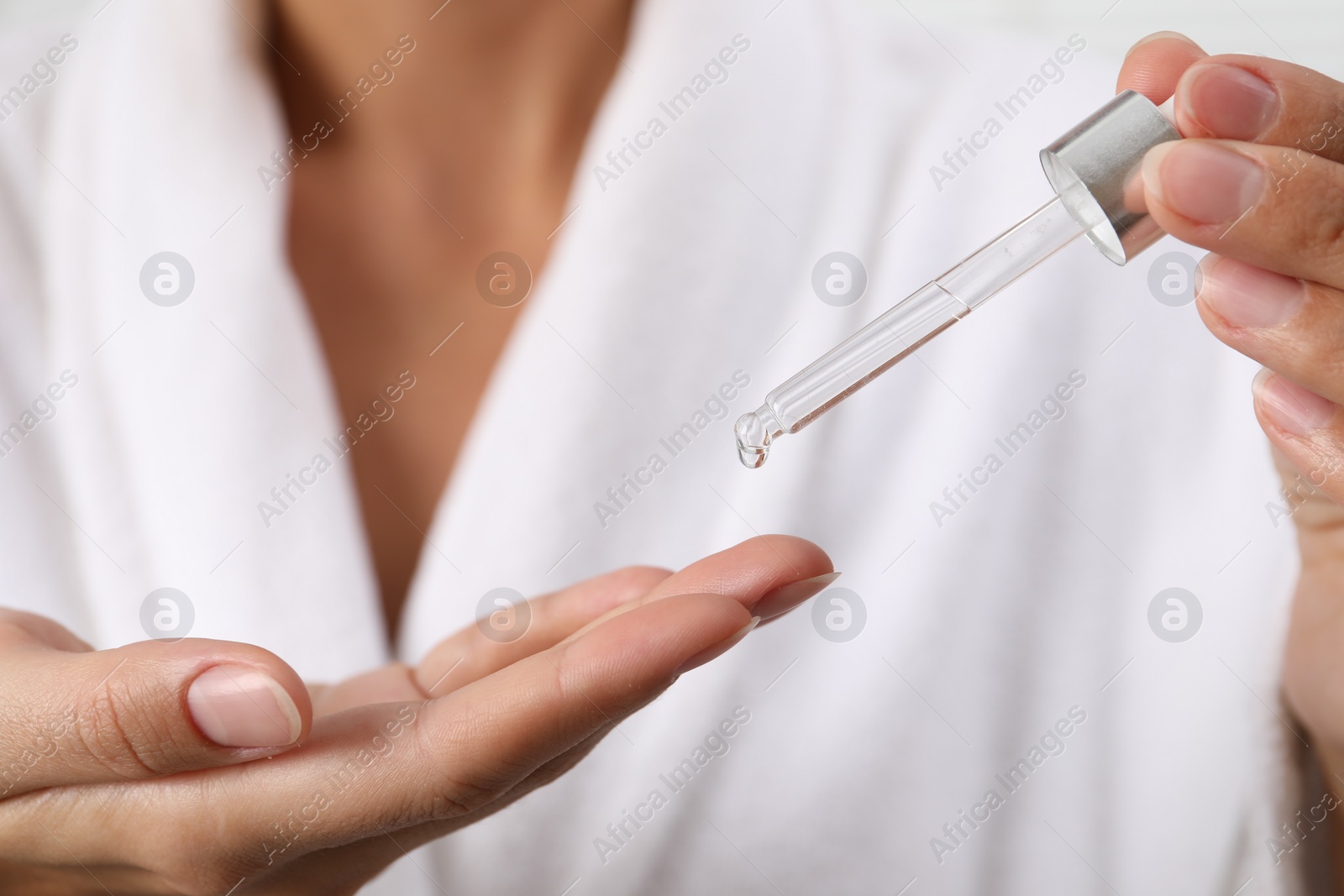 Photo of Woman applying cosmetic serum onto her finger, closeup